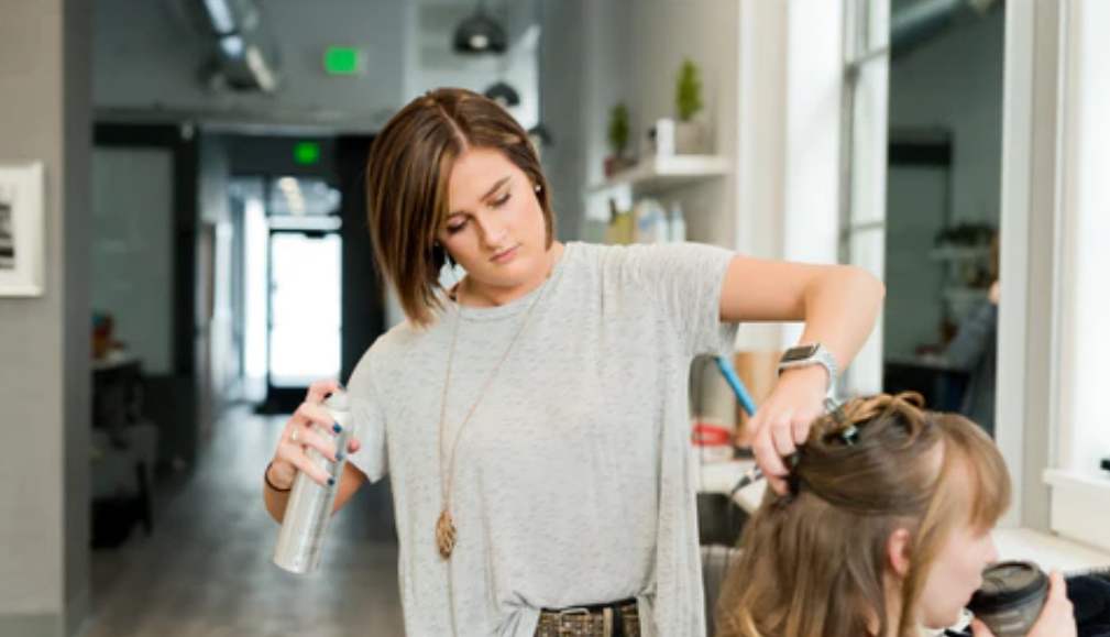 A hair stylist using dry shampoo on a client. Concept of dry shampoo uses, benefits.